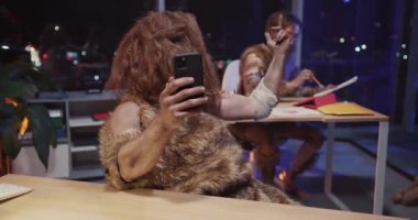 Modern cep telefonu kamerasıyla selfie çeken Savahe Kabilesi Çifti Şirket Ofisinde Birlikte Otururken Eğleniyor. Zamanda yolculuk. Mizah Konsepti.