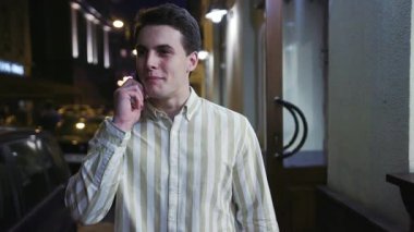 Portre genç adam akıllı telefon tebessümü ile konuşuyor. Etrafına bir bak. Geceleyin turist, modern mutlu iş adamları.