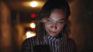 Müzik dinleyen alımlı genç bir kadın. Şehir caddesinde akıllı telefon kullanıyor. İnternette kadın yaşam tarzı telefon kızı.