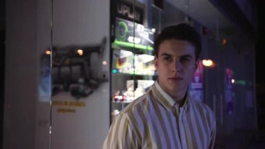 Yaklaş genç adam. Kameraya bak. Gece caddesinde ciddi dur. İş adamı başarılı bir yetişkin hücresi iletişimi.