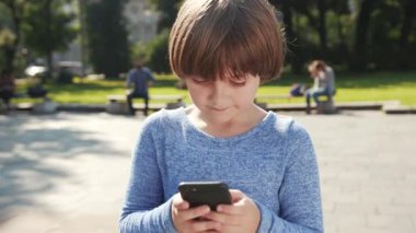 Küçük beyaz çocuk elinde cep telefonu ile ekrana bakıyor..