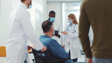 Çok ırklı Afrikalı cerrah ve kadın hekim terapist hastanedeki koridor boyunca yürüyorlar. Tıbbi ekip. Sağlık hizmetleri çalışanları. Klinikte işbirliği.