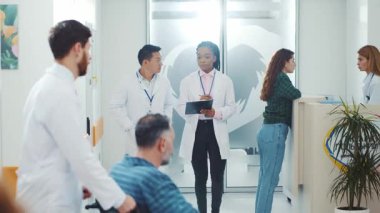 New York - 19 Mayıs 2018: Modern özel hastane profesyonel kliniğinde yürüyen çok ırklı yetişkin tıp çalışanları ve hastalar. Sağlık hizmetleri ortamı.