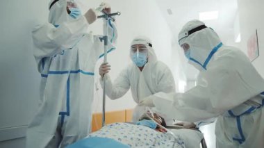 Yüzü maskeli sağlık görevlileri hastane koridorunda Coronvirus belirtileri gösteren sedye yatağı giyiyorlar. Salgın. Acil servis..