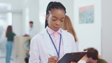 Çekici kadın pratisyen Afrikalı Amerikalı kadın hastane bekleme salonunda kamera karşısında pozitif gülümsüyor. Tıbbi kadın işçi. Sağlık personeli kavramı.