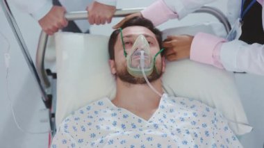 Hastane yatağında yatan bir adamın etrafı tıbbi personelle çevrili. Durumu için derin bakım ve tedavi uygulanıyor.