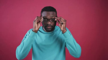 Elinde keçeli kalemle siyah gözlük takan, kameraya bakıp gülümseyen hoş bir Afrikalı. Renkli duvarın arka planında yakışıklı genç bir adamın portresi.