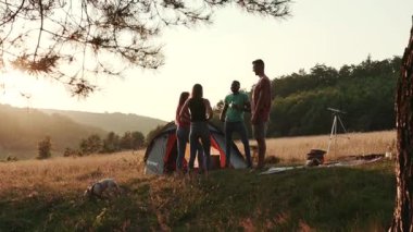 Bir grup genç arkadaş dışarıda eğleniyor. Bir grup arkadaş kamp tatilinde çadırların dışında dinleniyorlar. Yaz zamanı, macera, takılmak. Küçük barbekü partisi, piknik.