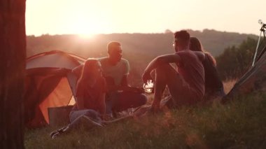 Bir grup arkadaş konuşuyor, gülüyor, gitarla birlikte şarkı söylüyor ve gün batımında çadırın dışında eğleniyorlar. Doğa, yürüyüş, kamp. Turizm konsepti, gerçek arkadaşlık, eğlenmek. Neşeli ruh hali