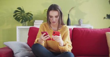 Üzgün genç bir kadın iki telefon kullanarak onları kanepeye fırlatıyor. Milenyum kızı evdeki kanepede otururken çok meşgul..