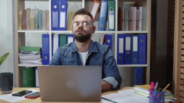 Ofis çalışanı, iş yerinde dizüstü bilgisayarın başında oturan ilham verici fikirleri düşünerek çok çalışmaktan yoruldu..