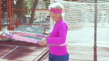 Canlı egzersiz kıyafetleri içinde kıdemli bir kadın hula hoplamaktan hoşlanır, aktif bir yaşam tarzını teşvik eder..
