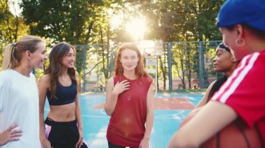 Canlı ve enerjik bir arkadaş grubu neşeli bir şekilde gülüyor ve canlı bir basketbol sahasında sporla meşgul oluyor.
