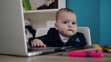 Meraklı ve tapılası bir bebek renkli bir dizüstü bilgisayarla etkileşime giriyor ve teknolojiyle erken teması gösteriyor.