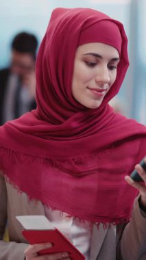 Kırmızı tesettürlü bir kadın günlerini, pasaportunu ve telefonunu kontrol ederek geçiriyor, bir kitaba dalıyor ve kişisel gelişim kavramlarını not alıyor.