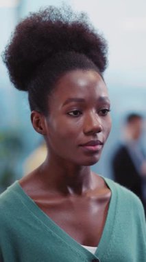 Sıcak gülümsemesi ve rahat yeşil hırkasıyla büyüleyen bir kadın sahneler düşünceli ifadesinden benzersiz afro saçlarına geçerken kendine güveni yayılıyor.