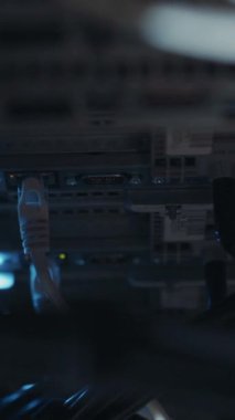 Karmaşık ethernet kablolarının bulunduğu loş bir sunucu odasında, karanlığın içinden geçen araba farlarının aksine, karmaşık dijital altyapıyı ima ediyor.