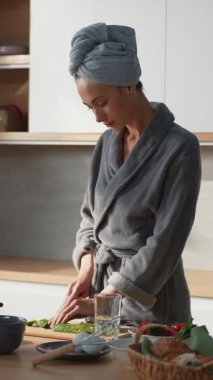 Güzel beyaz kadın evdeki mutfakta sağlıklı sebze salatası hazırlıyor. Salata için salatalık kesen güzel kadın..