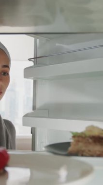 Kafkasyalı güzel bir kadın sağlıklı yiyeceklerle dolu buzdolabını açar ve bir pasta alır. Buzdolabının içinden POV.
