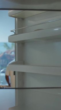 Ciddi bir Afro-Amerikan erkeği boş buzdolabını açıp içine bir parça kek koyar ve kameraya bakar. Buzdolabının içinden POV..