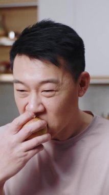 Portre yakışıklı genç adam mutfakta elma yiyor. Gülümseyerek mutlu ol. Meyve. Sağlıklı yiyecekler. Yavaş çekim