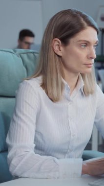 Modern ofiste bilgisayar kullanan iyi giyimli kadın ofis çalışanının portresi. Beyaz bluzlu beyaz bir kadının monitöre bakışının görüntüsü. İçeride. Gündüz vakti. Rahat bir yer..