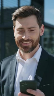 Başarılı, takım elbiseli, mutlu bir işadamı gülümseyen bir telefon kullanır ve gün ışığında sokaklara bakar. Yavaş çekim