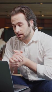 Portre çekici genç iş adamı, video konferansında, kafede dizüstü bilgisayar kullanarak konuşuyor. Uzaktan çalışıyor. Takım toplantısı. Yavaş çekim