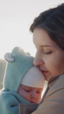 Güneşin batışında, göl kenarında doğan bebeğine bakarken gülümseyen bir annenin güzel görüntüsü. Mutlu annelik kavramı