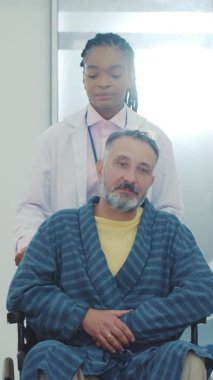 Hastane koridorunda engelli bir hastayla tekerlekli sandalyeye yakın durun. Engelli engelli, engelli, hastalık tedavisi ve hasta felci. Afrika kökenli Amerikalı terapistle.