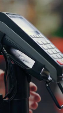 Yakın plan, süpermarkette ödeme terminali, satın almak için bağlantısız ödeme, NFC. Kadın eli telefonu ödeme için fesheder..