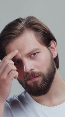 Yakın çekim aynası yansıması. Genç adam, kuru, sağlıksız cilt görünüşünden rahatsız olmuş. Yüz problemleri için endişeleniyor. Mutsuz adam yanağa dokunuyor, yağlı cilt ya da sivilceler üzerinde baskı hissediyor..