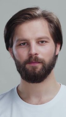 Beyaz tişört giyen sakallı genç adam stüdyo arka planında izole edilmiş moitsurizer krem kavanozu reklamı gösteriyor. Bencil bakım ürünleri.