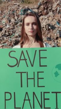 Tutkulu genç bir aktivist elinde parlak bir tabela tutarak acil gezegen koruma çabalarını savunuyor.
