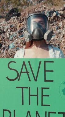 Gaz maskeli bir protestocu, atık sahasında temel çevre korumasını tutkuyla savunuyor.