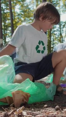 Kendini adamış genç bir gönüllü ormanda çöpleri temizliyor, çevresel bakımı ve sorumluluğu teşvik ediyor.