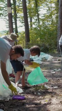 Aralarında bir çocuğun da bulunduğu gönüllüler, ağaçlık alandaki plastik atıkları temizliyor ve çevre bilincini artırıyor..