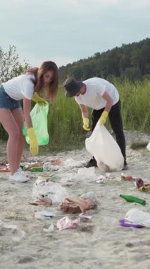 Adanmış gönüllüler daha yeşil bir gezegen için çöp toplamak amacıyla bir plaj temizleme etkinliğine katılmak için bir araya geliyorlar.