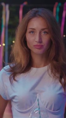 Uzun dalgalı saçları olan genç bir kadın neşeli bir açık hava partisi havasının keyfini çıkarıyor.