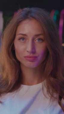 Renkli bir fon karşısında uzun, dalgalı saçları ve büyüleyici mavi gözleri olan bir kadının çarpıcı portresi..