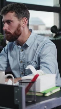 Bir adam şık bir ofis masasında, canlı bitkiler ve bir fincan sıcak kahveyle süslenmiş bir şekilde tamamen işine dalmıştır.