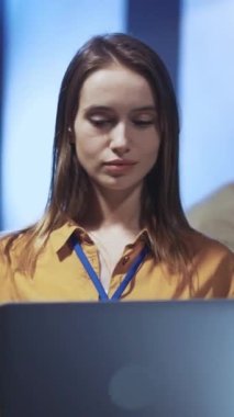 Genç bir kadın, modern bir iş ortamında özenle dizüstü bilgisayarı üzerinde çalışırken dikkatle konsantre oluyor.