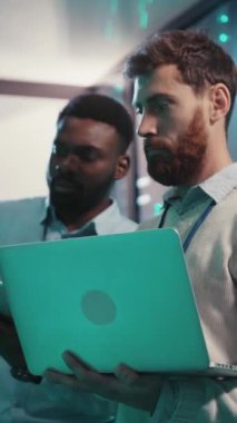 İki profesyonel modern dijital çalışma alanında dizüstü bilgisayarları üzerinde çalışırken veri içgörülerini tartışıyor