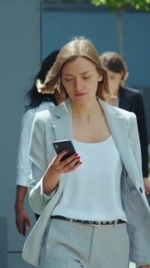 Şık, profesyonel bir kadın modern bir iş ortamında akıllı telefonuna odaklanır.