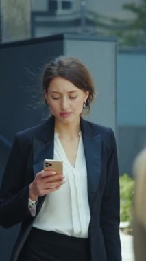 Şık giyinmiş genç profesyonel bir kadın bugün dışarıda akıllı telefonuyla meşgul.
