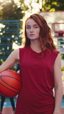 Bir bayan sporcu, sporun ve güçlenmenin özünü etkili bir şekilde gösteren bir basketbol topuyla kendine güvenle poz verir.