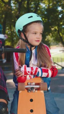 Renkli paten kıyafeti giymiş genç bir kız kaykay parkında eğlenirken güneşli güzel bir günün tadını çıkarıyor.