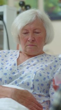 Hastane odasında şefkatle tedavi gören yaşlı bir kadın, sağlık hizmetlerinin önemini vurguluyor.