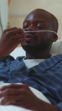 Bir hasta, gerekli oksijen desteğiyle bir hastane yatağında huzur içinde dinlenirken görülebilir.