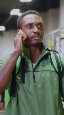 Spor giyim sektöründe bir adam akıllı telefonunu kontrol ediyor, modern yaşam tarzını ve teknolojik gelişmeleri yansıtıyor.